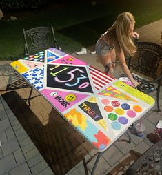 a woman sitting at a table painted with stickers on it and writing the number twenty five