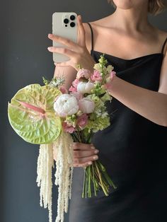 a woman taking a selfie with her cell phone and holding a bouquet of flowers