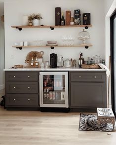 a kitchen with open shelves filled with wine bottles and glasses on top of the cabinets