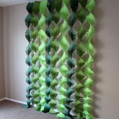 a green and white curtain hanging from the side of a wall next to a carpeted floor