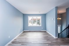 an empty room with blue walls and wood floors, painted in light blue tones on the far wall