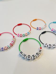 four bracelets with words written in different languages on them, sitting on a table