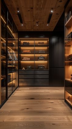 an empty walk - in closet with wooden floors and glass walls, lighted by recessed lighting