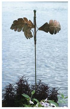 a tall metal sculpture with two leaves on it