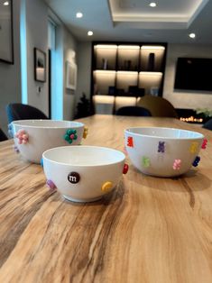 three white bowls sitting on top of a wooden table