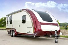 a red and white trailer parked on top of a parking lot next to a field