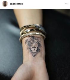 a woman's wrist with a lion tattoo on it