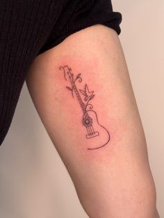 a woman's arm with a guitar tattoo on the left side of her body