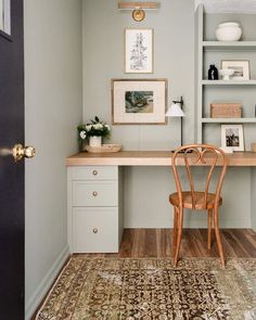 a desk with a chair and pictures on the wall above it in a home office