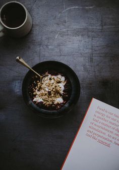 a bowl of oatmeal next to a book on a table