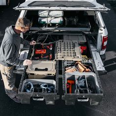 a man standing in the back of a white van filled with tools and equipment,