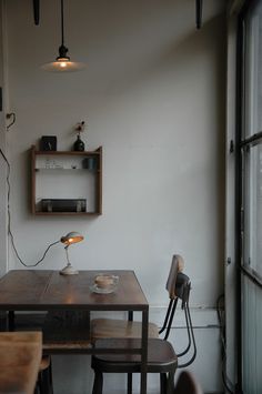 a wooden table sitting in front of a window next to two chairs and a lamp