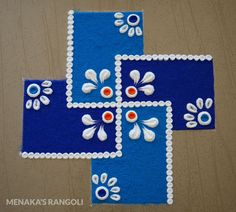 two pieces of blue and white felt with flowers on them, sitting on a wooden surface