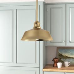 a kitchen light hanging over a counter top next to a painting on the wall and cupboards