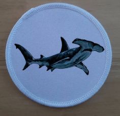 a patch with two dolphins on it sitting on a wooden table next to a bottle opener