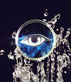 an eye is seen through a magnifying glass surrounded by water droplets and bubbles