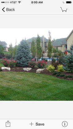 a yard with flowers and rocks in the grass next to a fenced in swimming pool