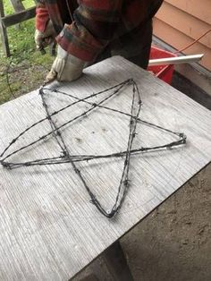 a person working on an object made out of barbed wire and metal rods with the shape of a star attached to it