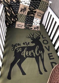 a crib bed with a green and black deer blanket on it's side