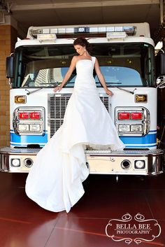 a woman in a wedding dress standing on the front of a firetruck with her hands on her hips