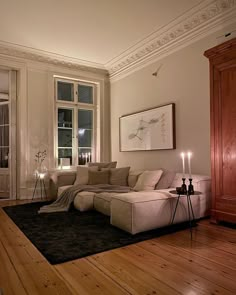 a living room filled with furniture next to a window covered in candles and artwork on the wall