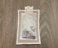 a piece of paper with an image of a deer in the woods on it's side