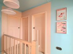 there are two pictures on the wall above the stairs in this room, one is pink and the other is blue