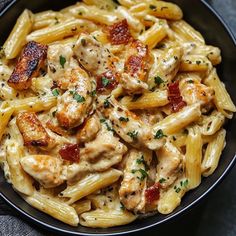 pasta with chicken and sauce in a black bowl