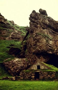 a large rock formation sitting on top of a lush green hillside