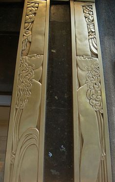 two doors with decorative designs on them in an area that looks like it has been painted gold