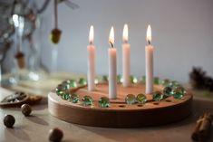 a candle holder with five candles and green glass beads on it, surrounded by other decorations