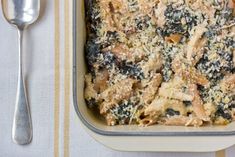 a casserole dish with spinach, cheese and bread crumbs on top