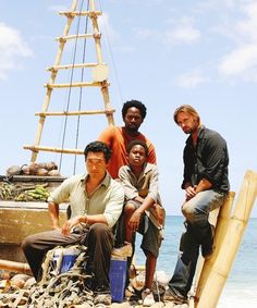 three men sitting on the back of a boat in the ocean with other men standing around