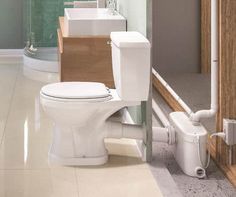 a white toilet sitting in a bathroom next to a sink and shower head mounted on a wall