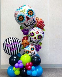 a bunch of balloons that are in the shape of skulls with flowers and stripes on them