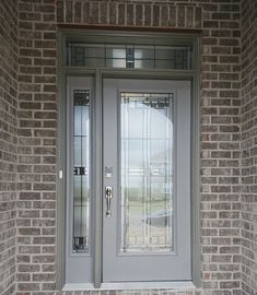 the front door is made of brick and has two glass panels on each side, along with a metal handle