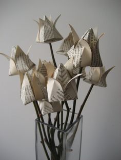 origami flowers in a glass vase made from old book pages with writing on them