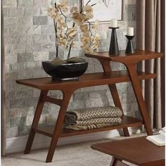 a wooden table with vases and flowers on it in front of a stone wall