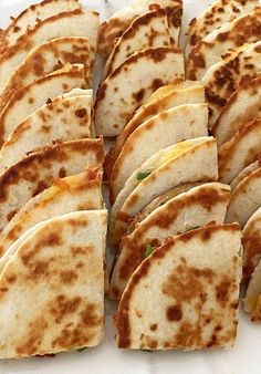 several quesadillas are arranged on a white platter and ready to be eaten