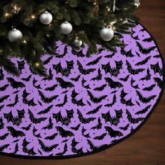 a christmas tree with bats on it in front of a purple and black circular background