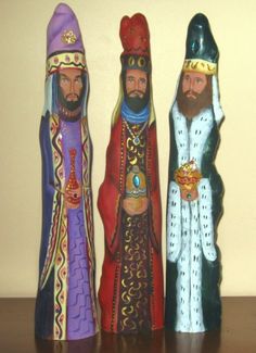 three figurines are standing next to each other on a wooden table with a wall in the background