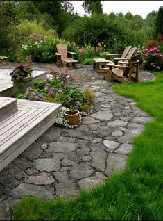 an outdoor patio with chairs and flowers in the back ground, surrounded by green grass