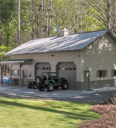 two jeeps parked in front of a garage on the side of a road next to trees