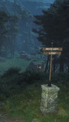 a wooden sign sitting on the side of a lush green field next to a forest