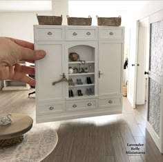 a person is holding a miniature cabinet with shoes on the top and bottom shelves in front of them