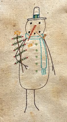 an embroidered snowman holding flowers on a piece of cloth