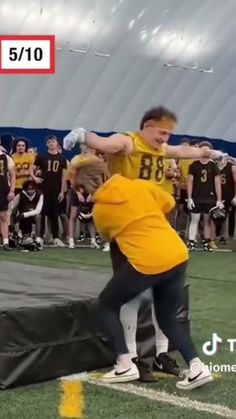 two young men are wrestling on the football field