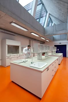 two men in white lab coats are working on the sinks and counter tops inside an orange floored room