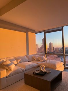 a living room filled with furniture and large windows overlooking the cityscape in the distance