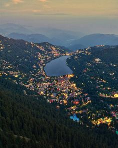 an aerial view of a city and lake at night with mountains in the background,